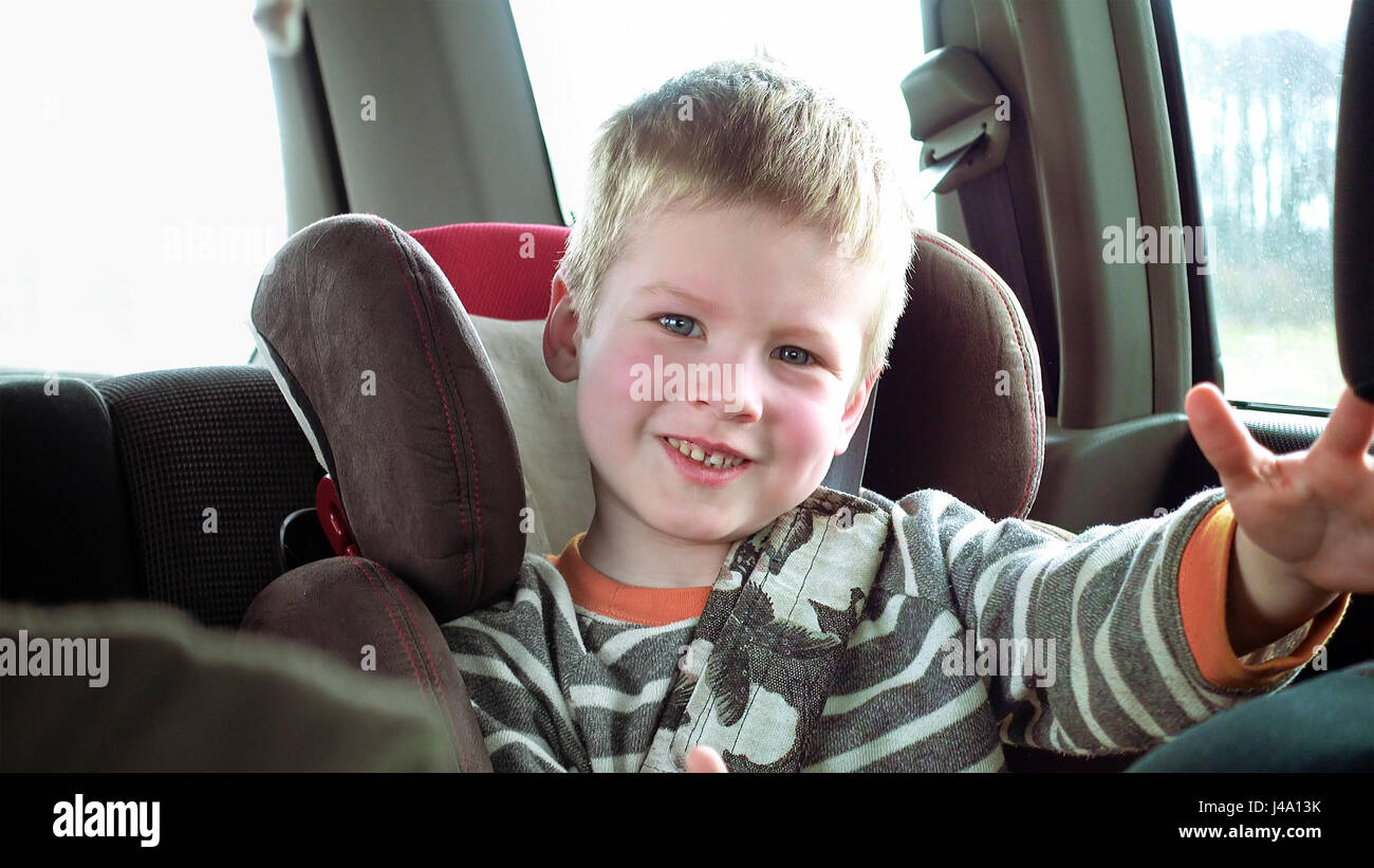 Süsser Boy im Auto Kindersitz lächelt und lacht Stockfoto