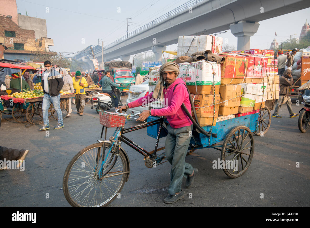 Man zieht einen Fahrrad-Wagen tragen mehrere Boxen in einer belebten Straße in Neu-Delhi, Indien. Stockfoto