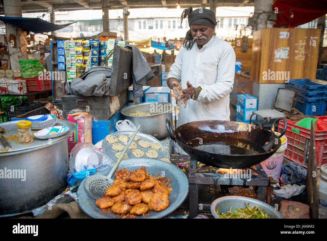 Ein Mann kocht traditionelle indische Lebensmittel auf einem Markt in der Innenstadt von New Delhi, Indien. Stockfoto