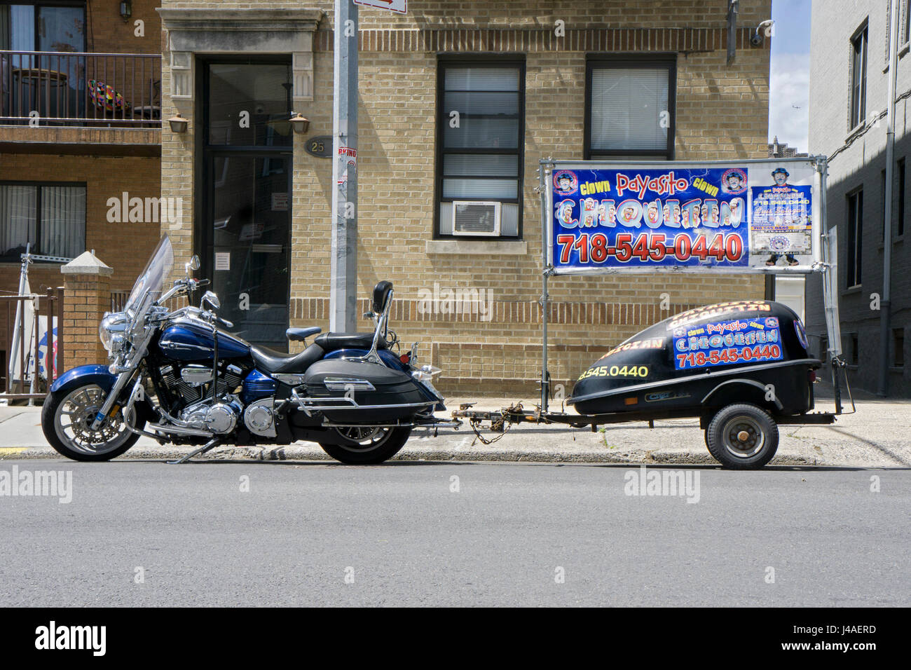 Ein Motorrad mit einem kleinen Anhänger mit Werbung für Payasito Chiquitin, lateinamerikanischen Clown. In Astoria, Queens, New York City. Stockfoto