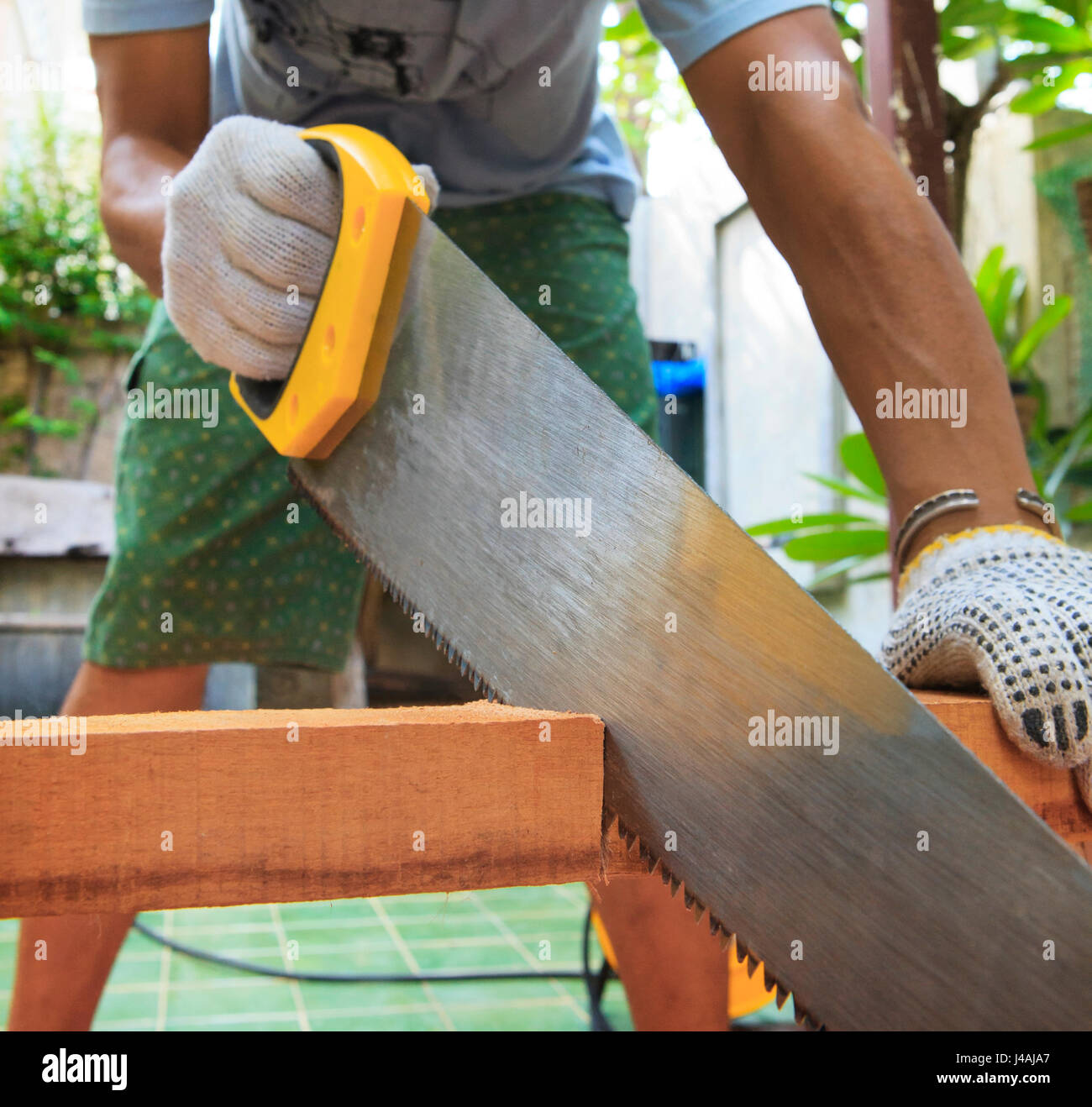 junger Mann Holzsägen zu Hause für DIY-Arbeits- und Pflege zu Hause in Urlaub und männliche Aktivitäten Stockfoto