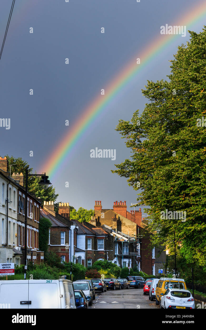 Ein heller Regenbogen an einem regnerischen Nachmittag über eine Wohnstraße der viktorianischen Reihenhäusern in Islington, London, UK Stockfoto