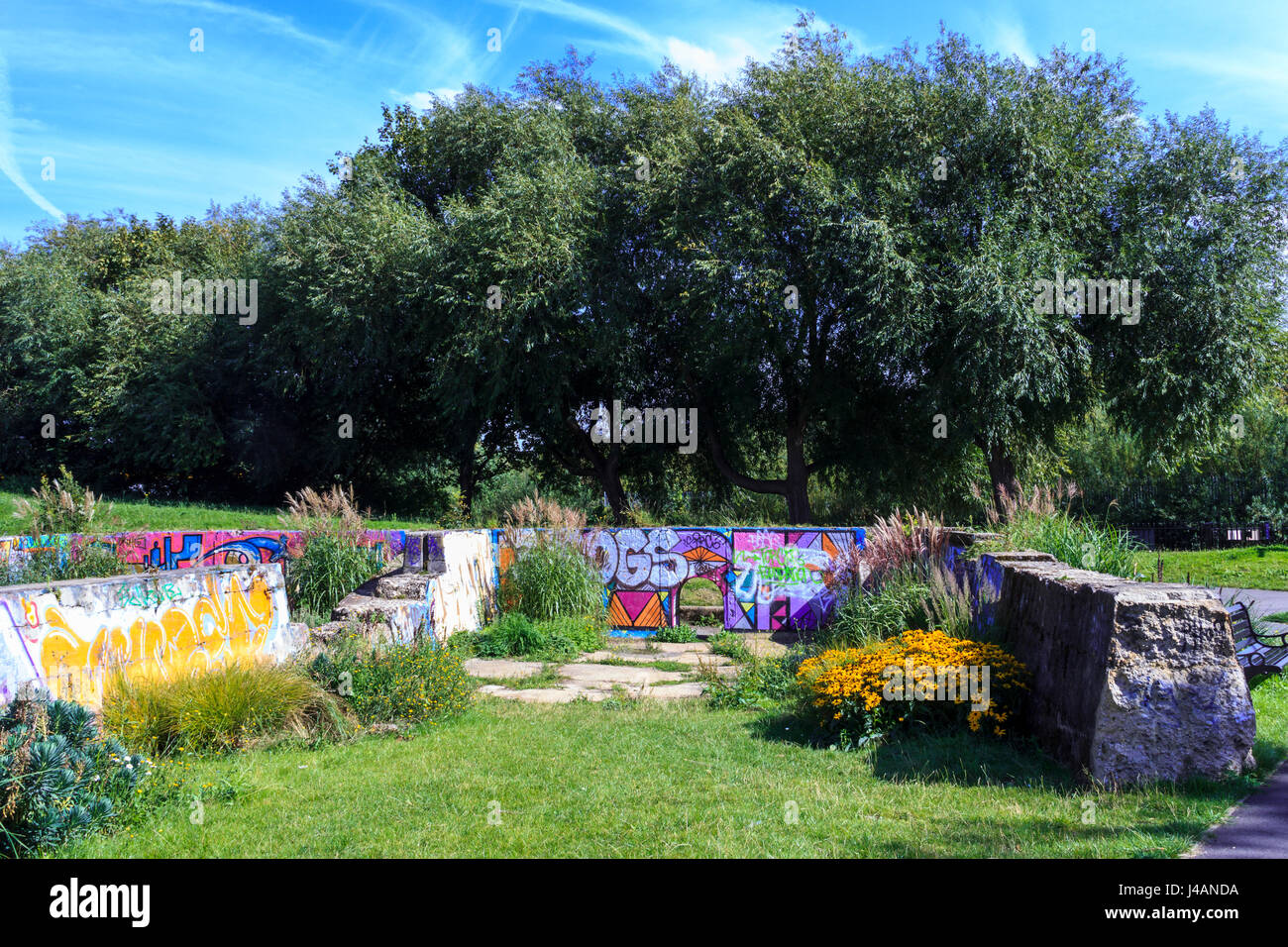 Der viktorianische Abwasserkanal Betten in Markfield Park, Tottenham, London, UK, bepflanzt mit Blumen und mit Graffiti verziert Stockfoto