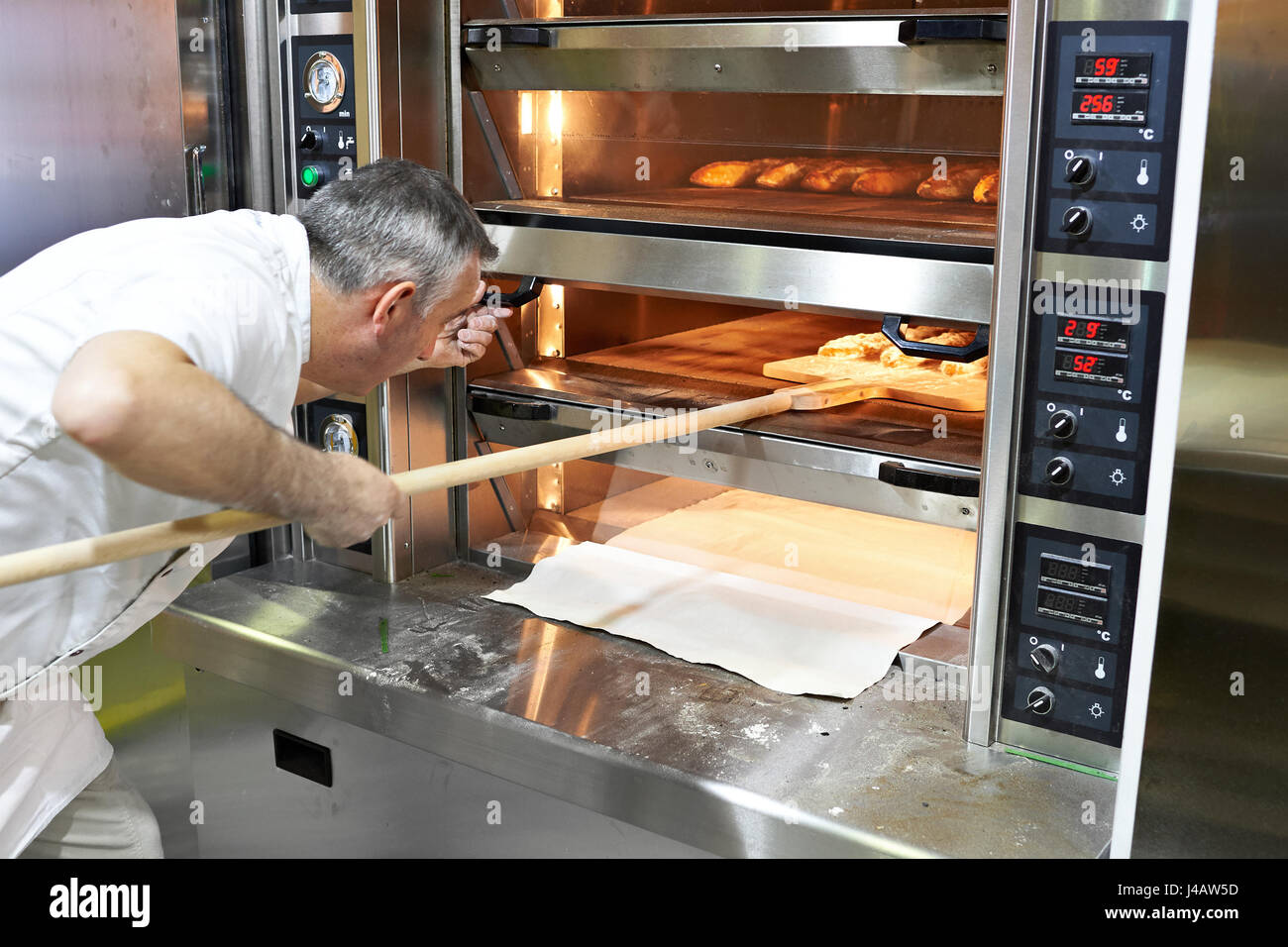 Bäcker backt Brot im Backofen Stockfoto