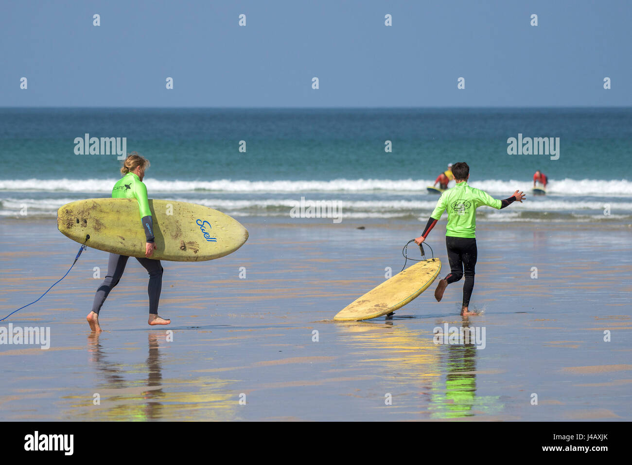 Begeisterte Surf Schule Novizen ausgeführt, um das Meer entkommen Surf Schule Fistral Strand Newquay Cornwall Surfen Surfer Lernenden lernen scharf Stockfoto