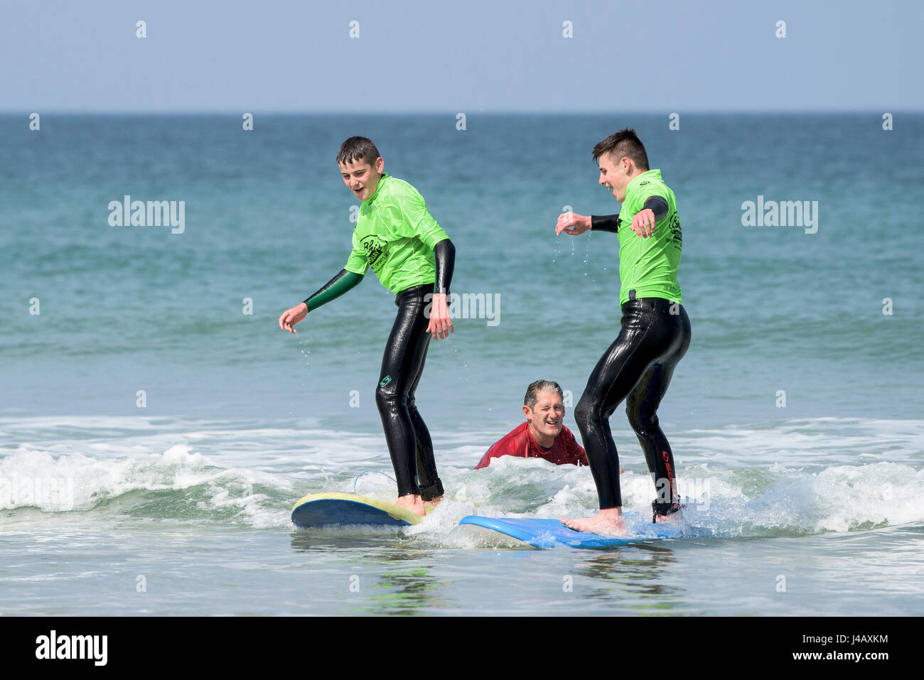Novizen auf Fistral Beach in Newquay Cornwall entkommen Surfen Surfen lernen Schule Surfen Surfer Lernenden lernen Lehrer helfen am Meer Meer Stockfoto