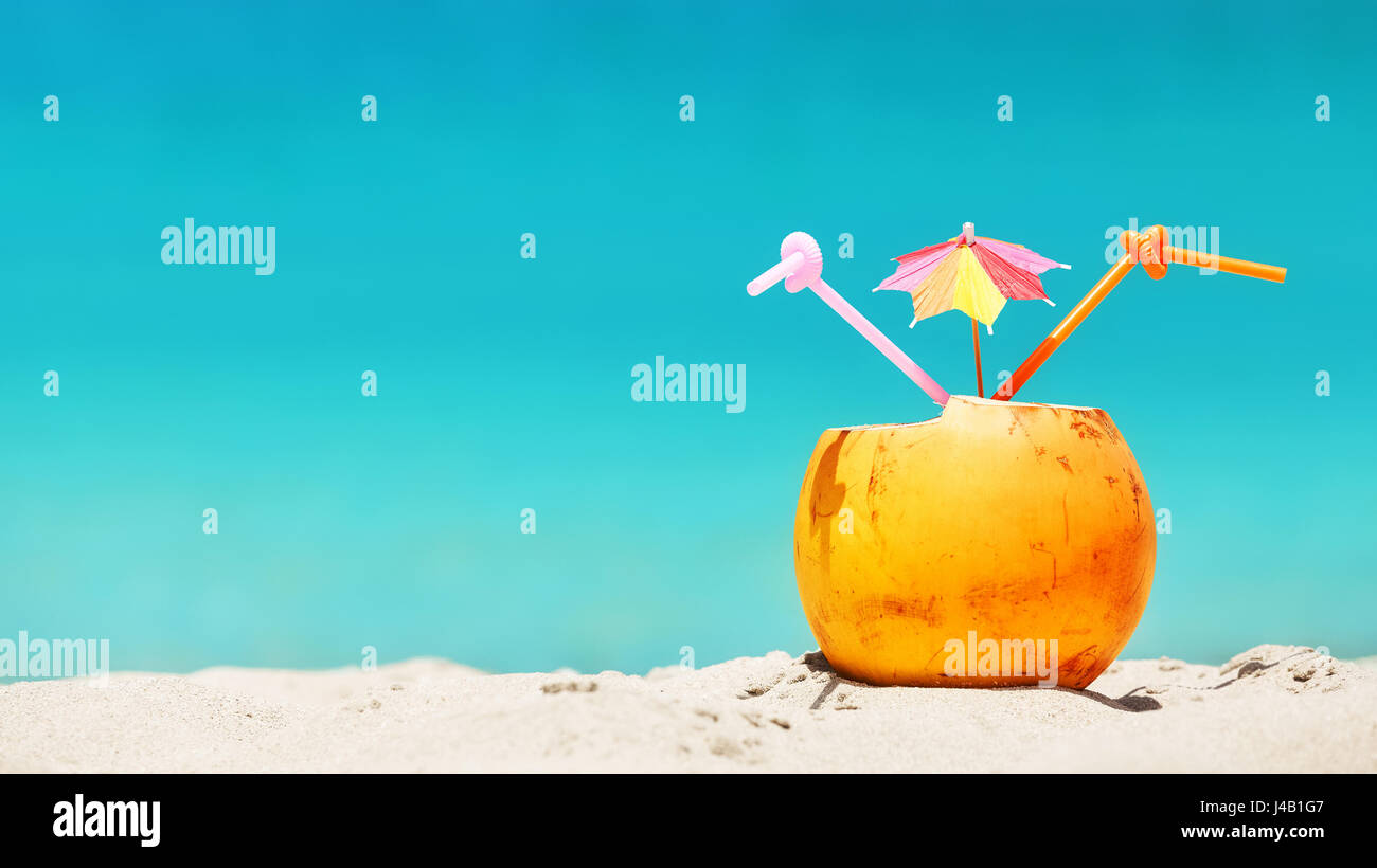 Kokosnuss mit Strohhalm und bunten cocktail Regenschirm auf einem tropischen Strand, Sommer Urlaub Konzept, Tiefenschärfe, Platz für Text. Stockfoto