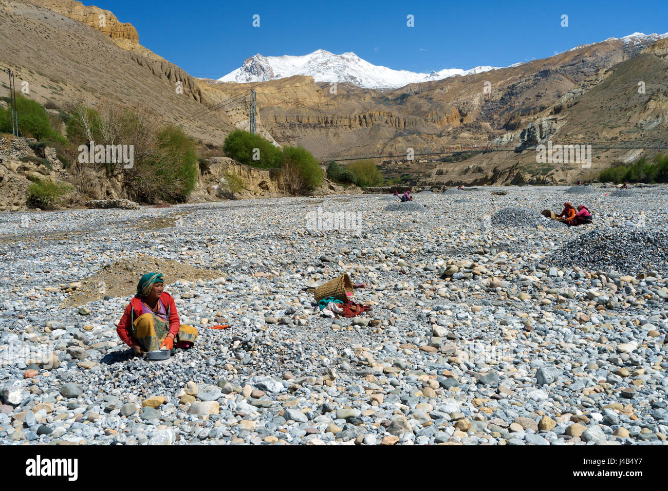 Nepalesische Frauen brechen Felsen im trockenen Flussbett des Kali Gandaki River, Chuksang, Upper Mustang, Nepal. Stockfoto