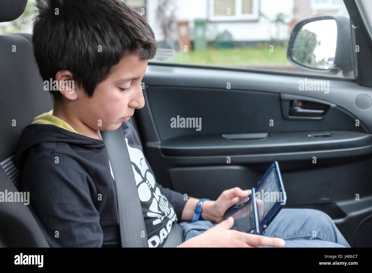 Junge, 10 Jahre alt, spielt Computerspiel in Auto, UK Stockfoto