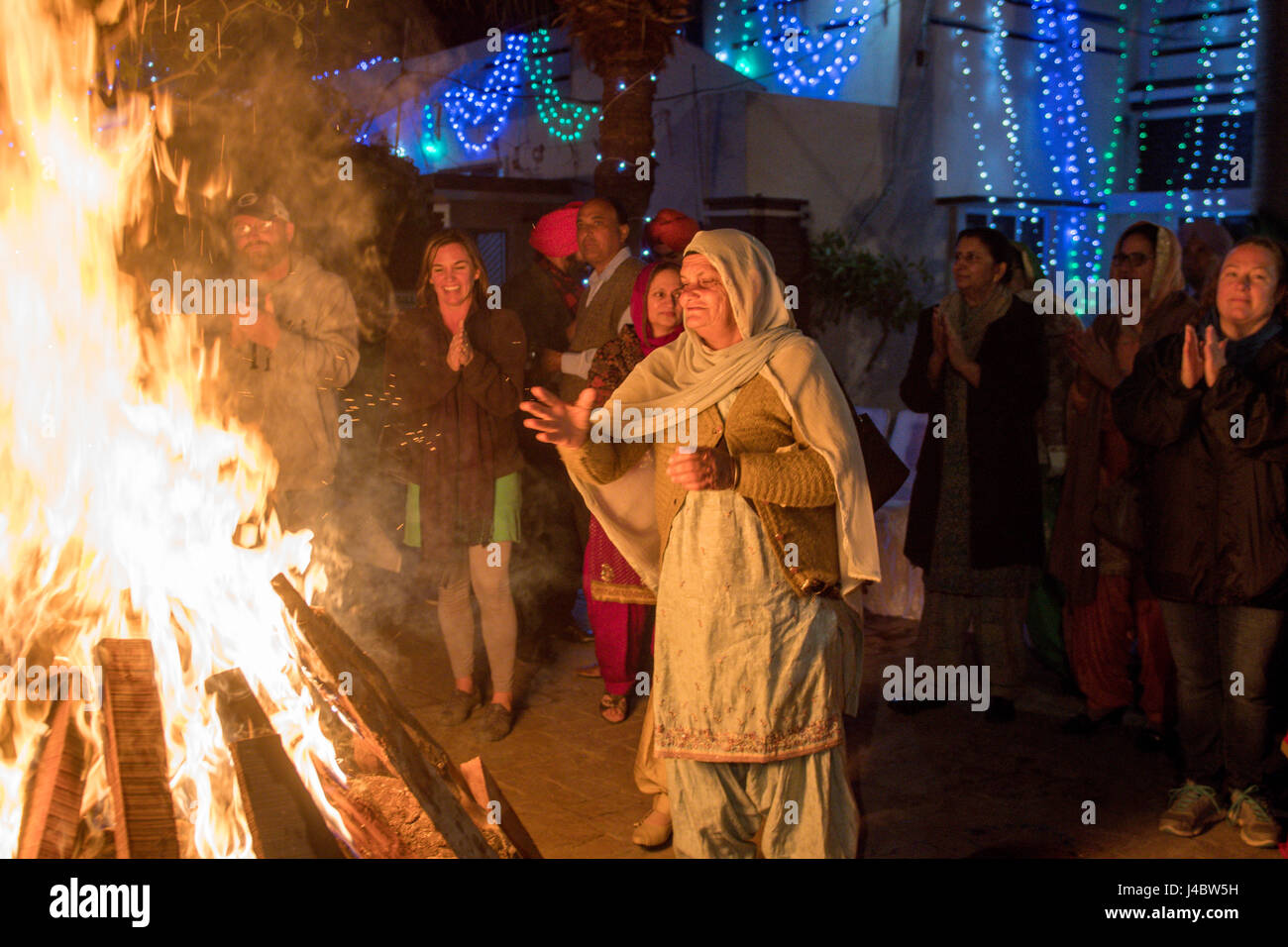 Eine Punjabi Frau wirft Samen ins Feuer beim Lohri fest. Es ist Tradition, kleine Gegenstände in das Feuer, um Respekt, Feuer werfen Stockfoto