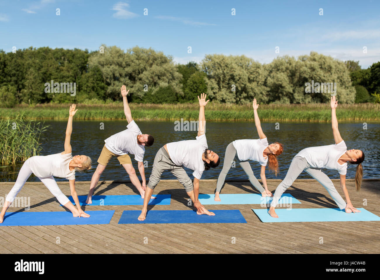 Menschen, die Yoga im linken Dreieck-Pose im freien Stockfoto