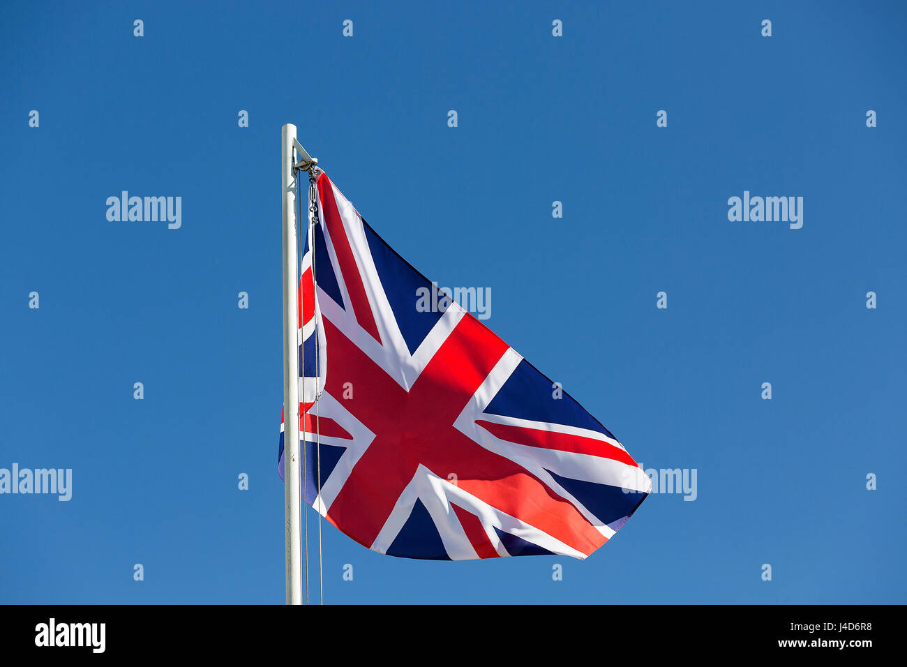 Britische Flagge am Fahnenmast vor blauem Himmel Stockfoto