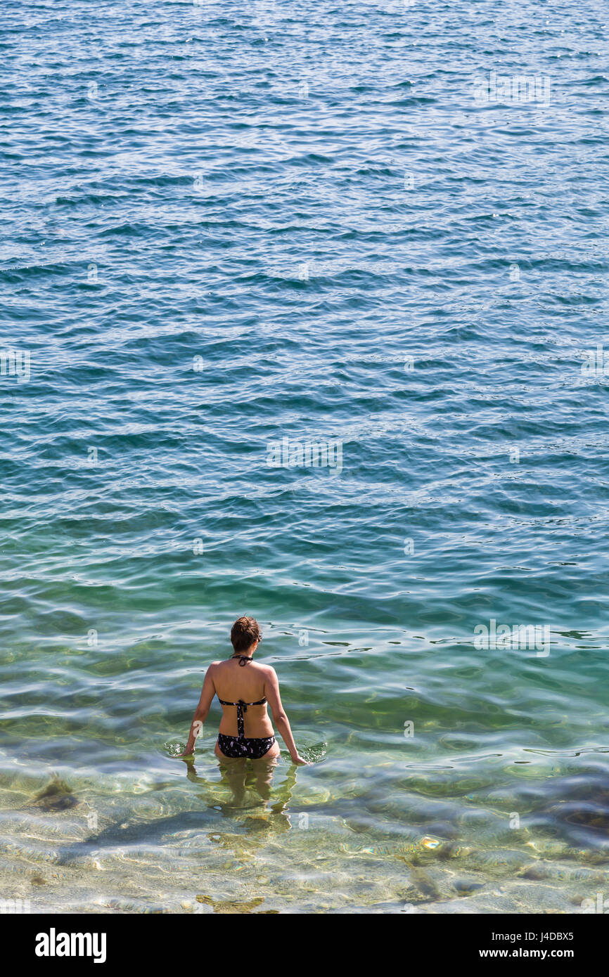 Eine junge Frau beginnt um sich abzukühlen, wie sie sich in das klare Wasser in der Bucht von Kotor. Stockfoto