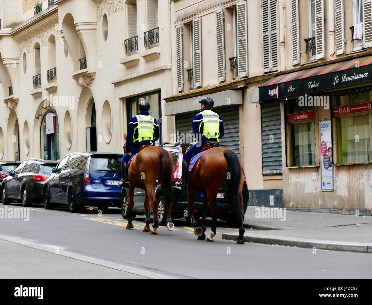 Zwei Gendarmen, bewaffnete Polizei, reiten Pferde die Straße hinauf auf Patrouille, rue de Championnet, 18. Arrondissement, Paris, Frankreich. Mai 2017 Stockfoto