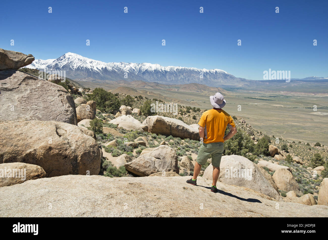 dem Rücken eines Mannes, der Blick auf die Berge der Sierra Nevada von einem Aussichtspunkt auf den Druiden-Steinen in der Nähe von Bischof California Stockfoto