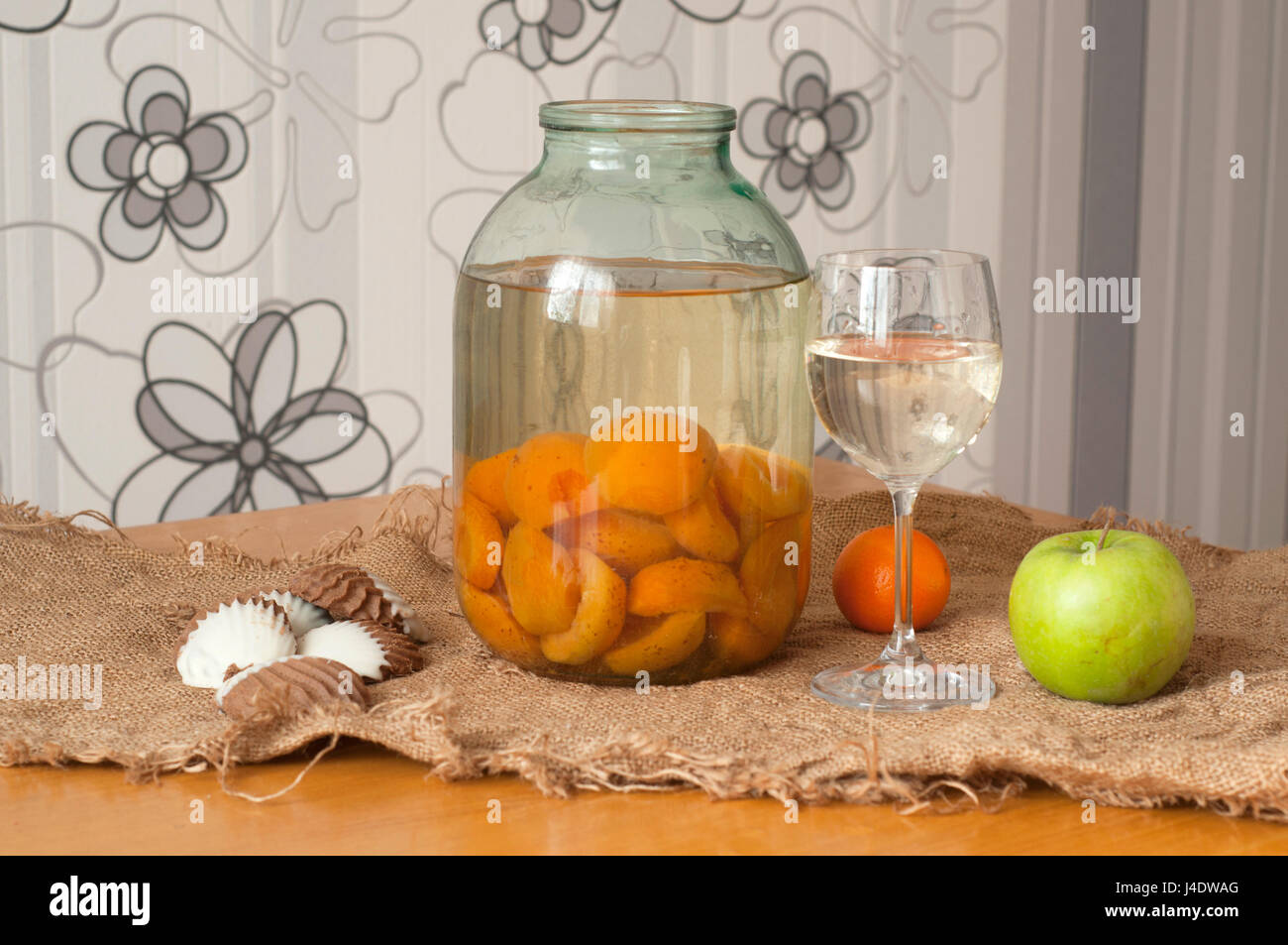 Ein Glas und ein Glas mit Kompott von Aprikosen, Kekse und Obst auf dem Tisch Stockfoto