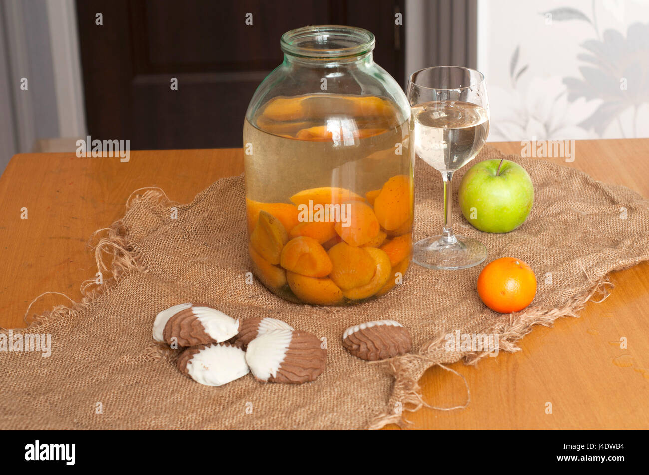 Ein Glas und ein Glas mit Kompott von Aprikosen, Kekse und Obst auf dem Tisch Stockfoto