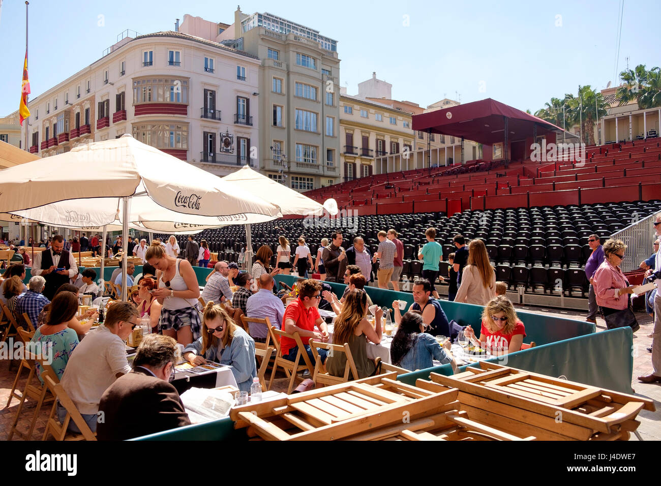 In der Karwoche die Menschen Sie sitzen in Cafés auf der Plaza De La Constitución, Malaga vor leeren Tribünen, die im Laufe des Tages mit Peo verpackt werden Stockfoto