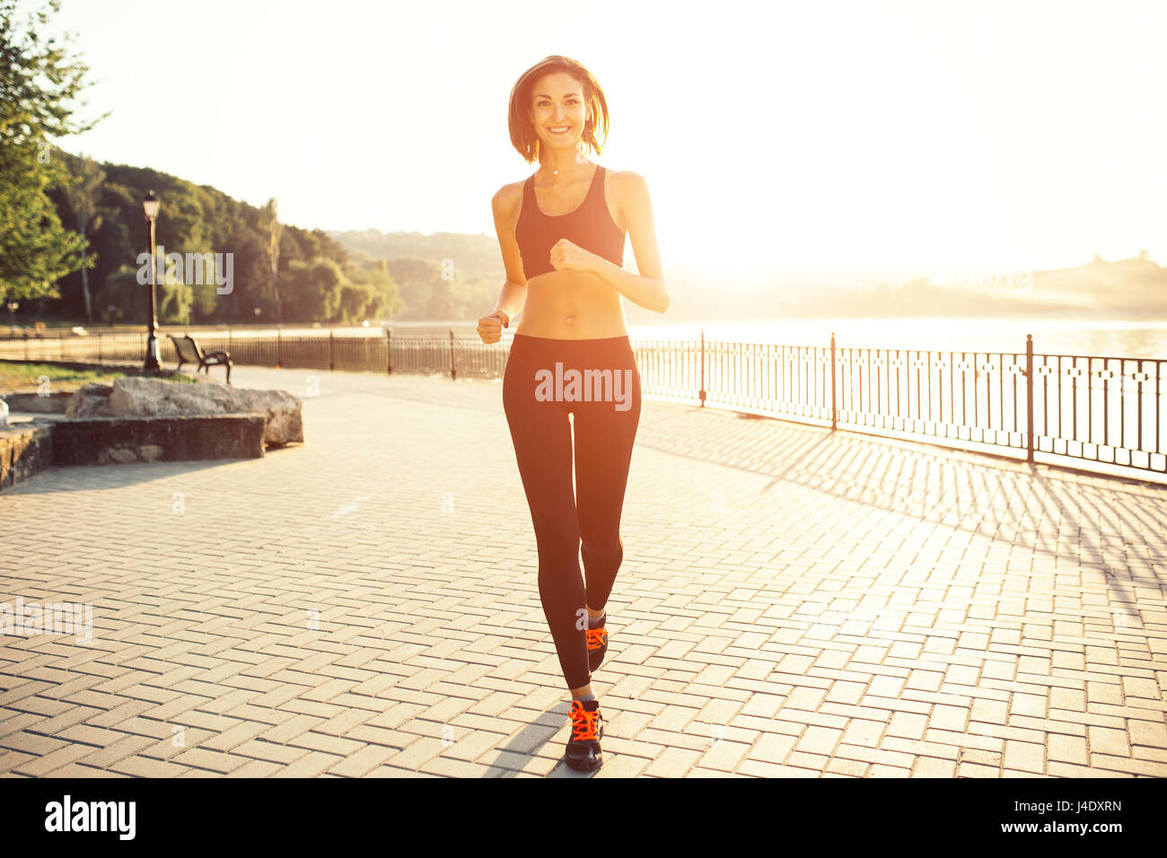 Frau läuft am See bei Sonnenuntergang. Sport- und Lifestyle-Konzept Stockfoto