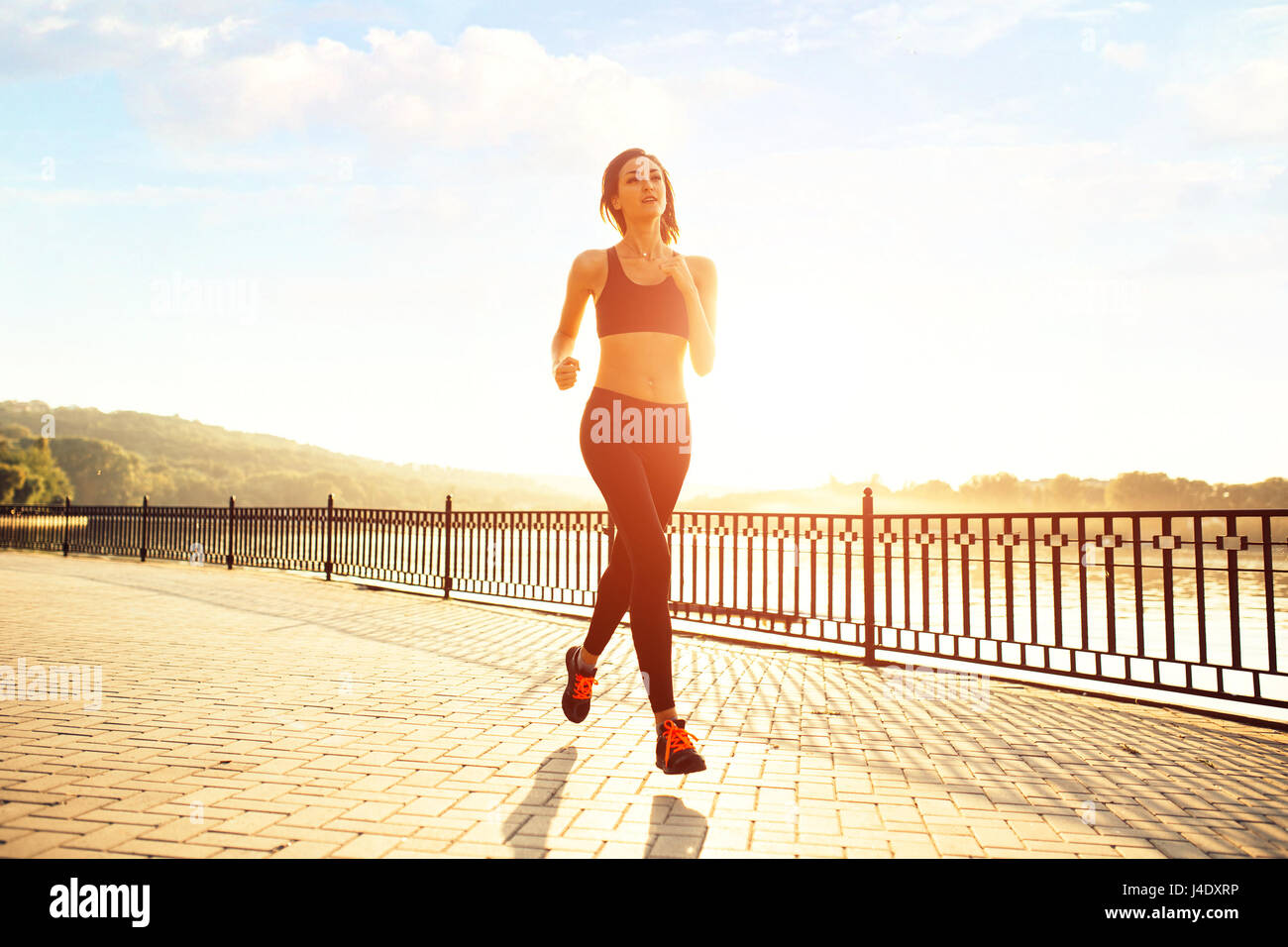 Frau läuft am See bei Sonnenuntergang. Sport- und Lifestyle-Konzept Stockfoto