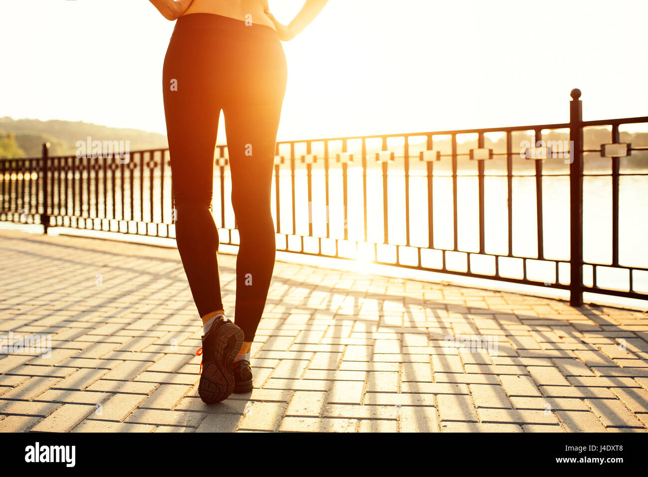 Frau läuft am See bei Sonnenuntergang. Sport- und Lifestyle-Konzept. Füße-Nahaufnahme Stockfoto