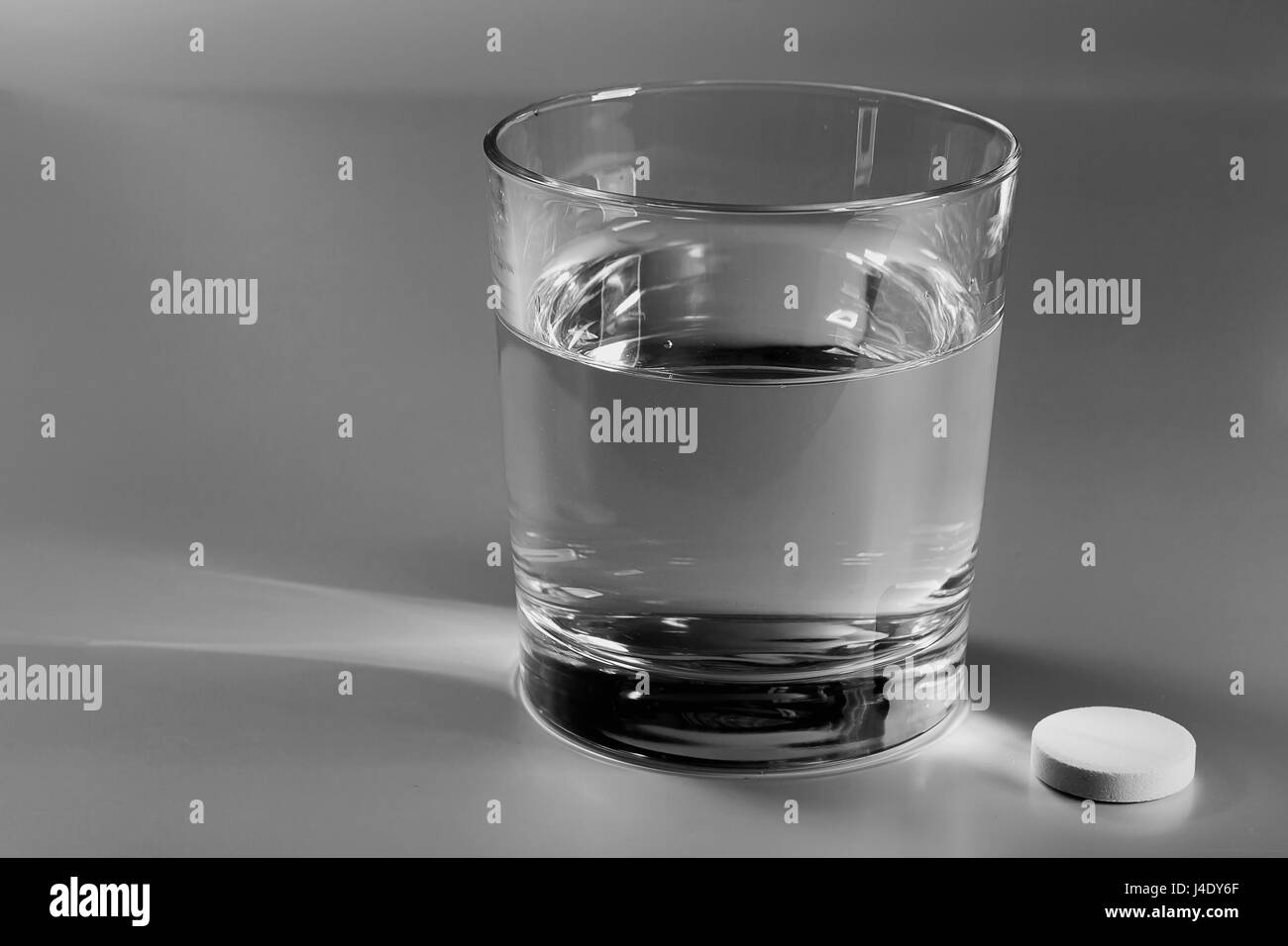 Glas Wasser auf dem Tisch und eine Brause Pille daneben Stockfoto