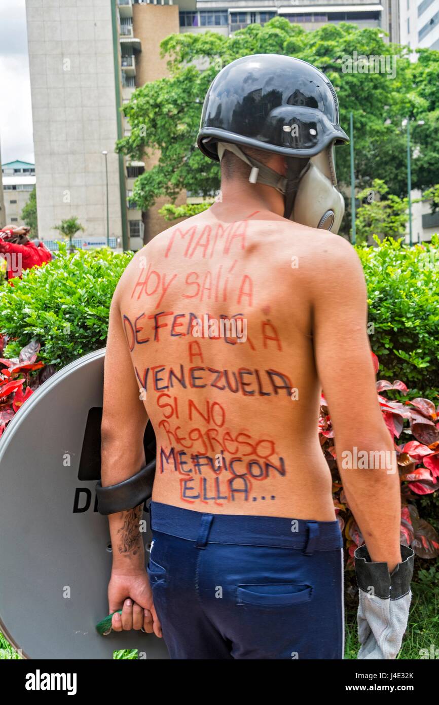 Ein junger Mann schreibt auf dem Rücken... "Mama, oder ich Links für Venezuela zu kämpfen, aber ich ging mit ihr zurück". Unter dem Motto "Unser Schild ist die Verfassung", oder auch genannt den "Marsch der Schilde", Demonstranten begann sich in den verschiedenen Teilen der Stadt, Supreme Court of Justice (TSJ) zu erreichen. Caracas, 10. Mai 2017 Stockfoto
