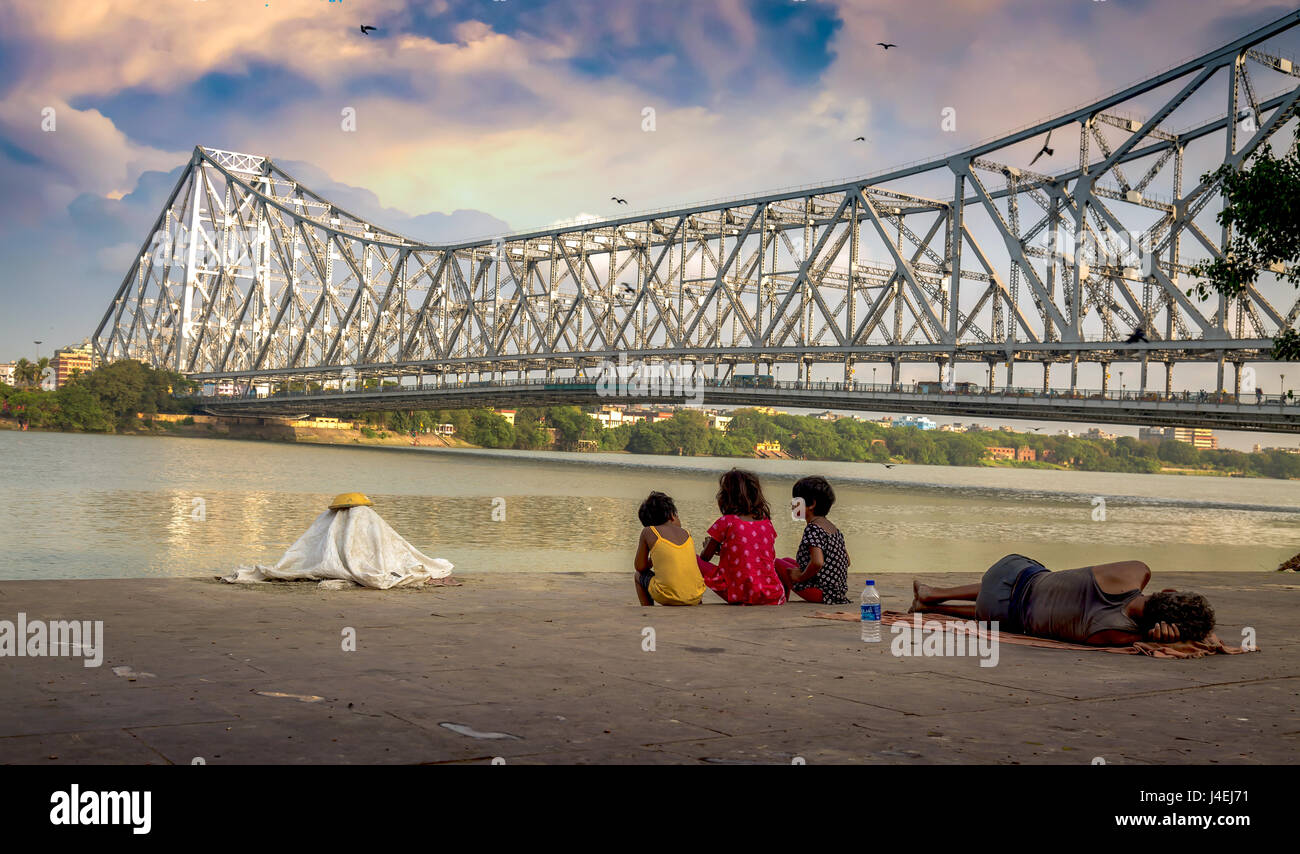 Street Kids genießen Sie den Blick auf das howrah Bridge aus dem hooghly River Bank mallick Ghat, Kolkata, Indien. Stockfoto