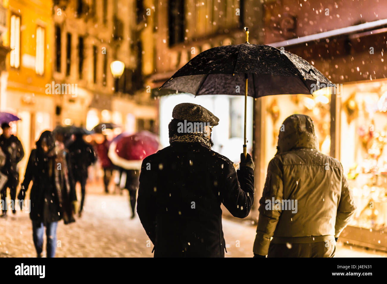 Menschen in Einkaufsstraße mit Sonnenschirmen bei seltenen Schneefall, Winterabend, UNESCO-Weltkulturerbe, Veneto, Venedig, Italien Stockfoto