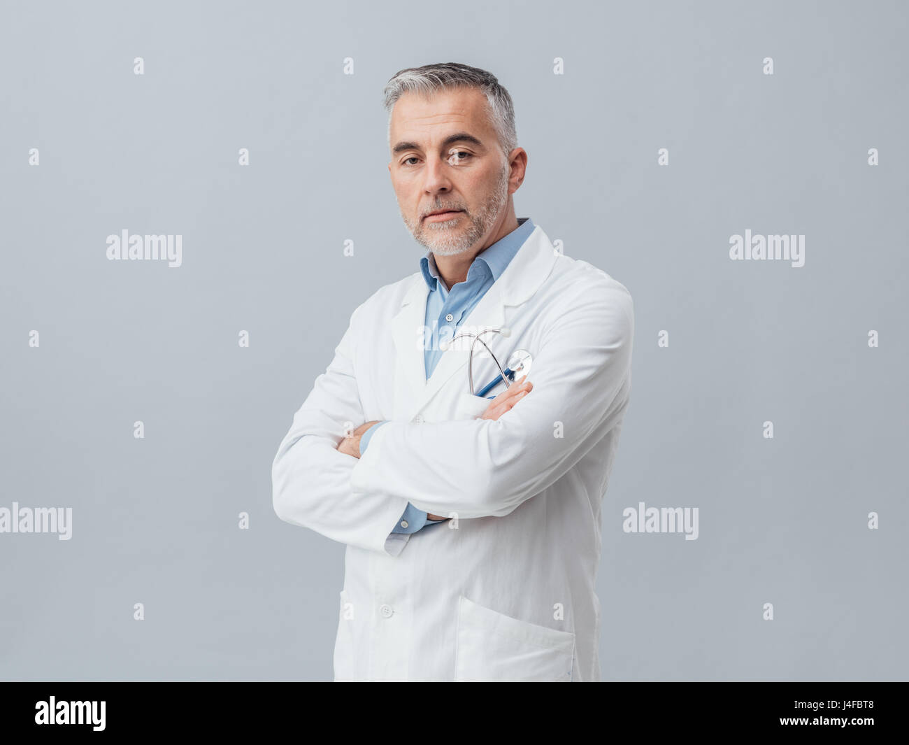 Zuversichtlich Arzt posiert mit verschränkten Armen und Blick in die Kamera Stockfoto