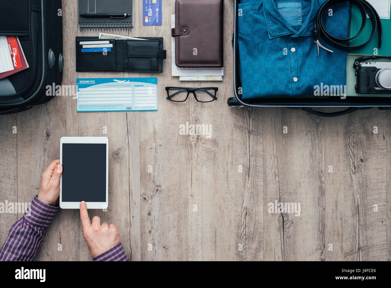 Mann, Verpackung für eine Reise er mit einer digitalen Touch-Screen-Tablette und Flüge online buchen mit einer mobilen app lag flach Banner Stockfoto