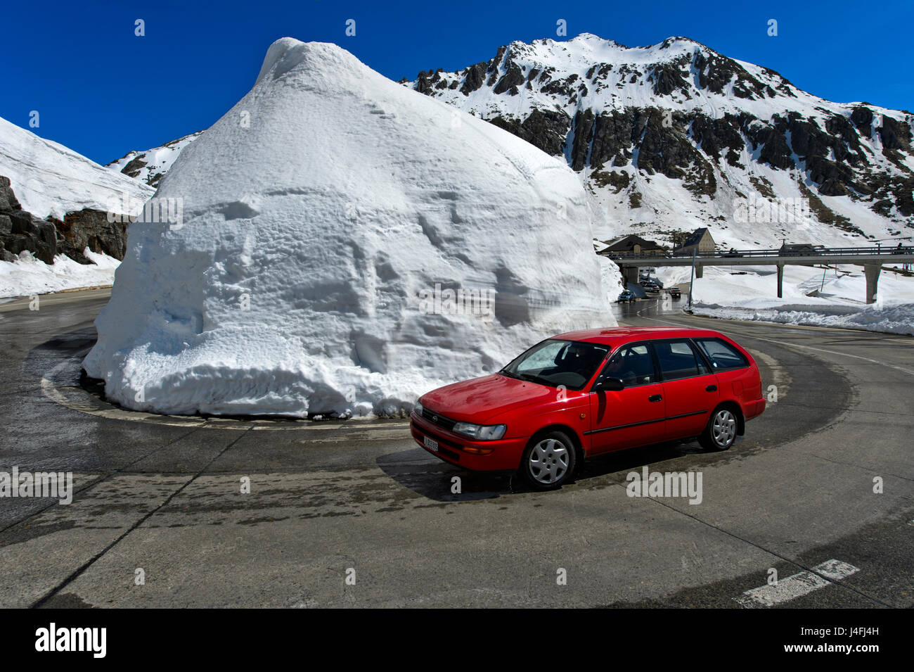 Haarnadelkurve um einen Haufen Schnee von der Passstrasse über den St. Gotthard Pass, St. Gotthard Pass, Kanton Tessin, Schweiz Stockfoto