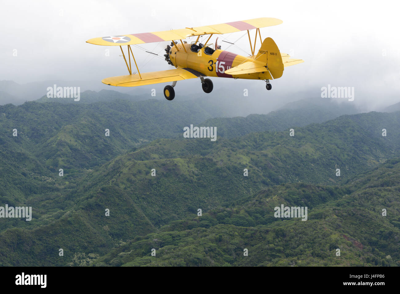 Harry Greene Wellen während des Fluges sein Flugzeug Boeing Stearman Kaydet Anfängerschulflugzeug über Oahu, 30. Mai 2016. Greene ist ein Hubschrauberpilot bei Coast Guard Air Station Barbers Point und ein Flugzeug-Enthusiasten in seiner Freizeit Zeit. (Foto: U.S. Coast Guard Petty Officer 2. Klasse Tara Molle/freigegeben) Stockfoto