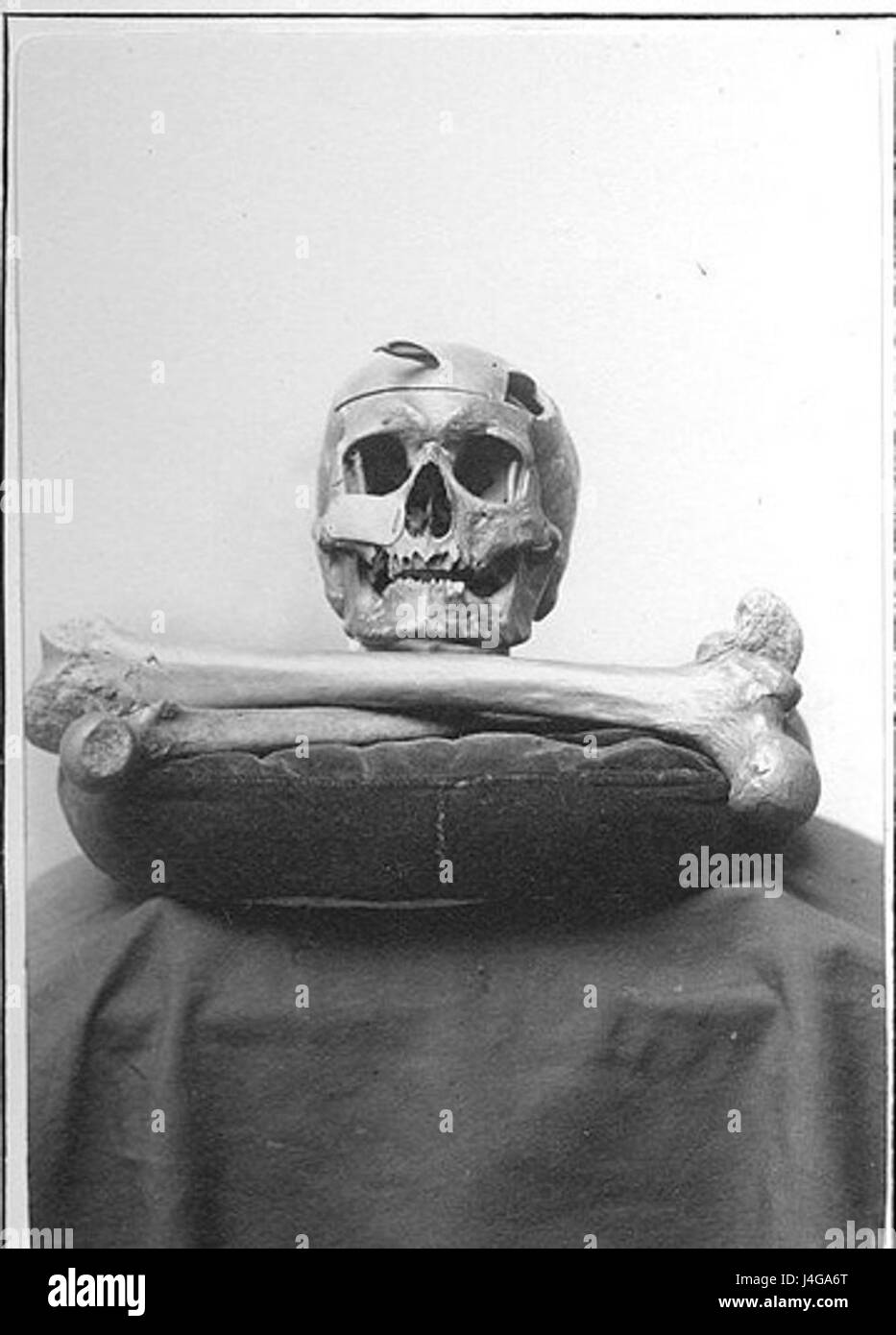 Das Bild zeigt einen Schädel und Knochen auf einem Kissen, oft verbunden mit Memento Mori, das als Symbol für die Sterblichkeit und die Vergänglichkeit des Lebens dient. Stockfoto