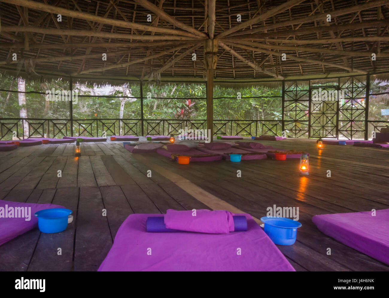 Das Innere einer traditionellen strohgedeckten Hütte verwendet für Ayahuasca-Zeremonien, komplett mit Matten, Kissen und Erbrochenem verblasst. Stockfoto