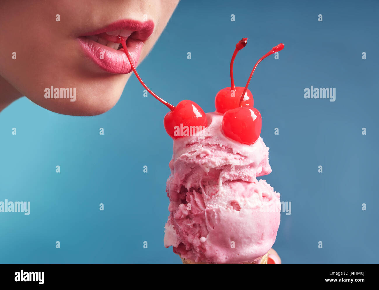 Nahaufnahme von rosa Eistüte dekoriert mit Cocktail-Kirsche vor die Lippen Frau Stockfoto
