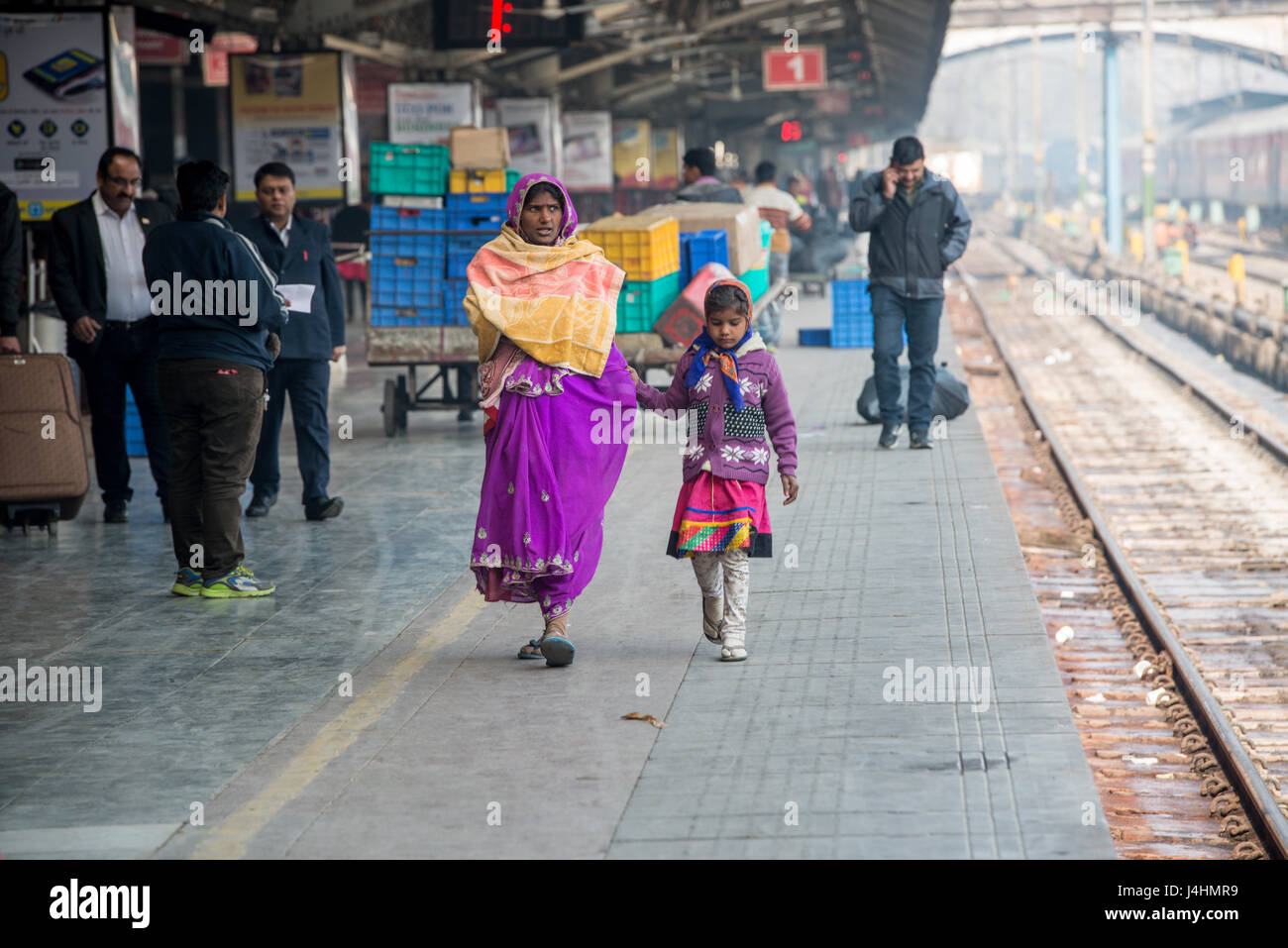 Eine Mutter und Tochter gehen auf einem Bahnsteig an einem Bahnhof in New Delhi, Indien. Stockfoto