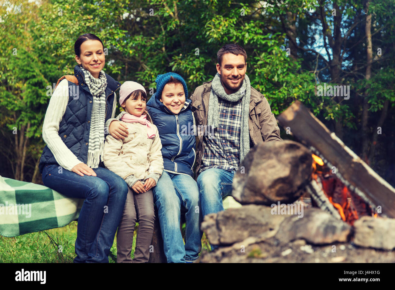 Glückliche Familie sitzt auf der Bank am Lagerfeuer. Stockfoto