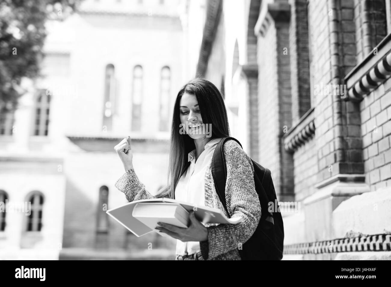 Lächelnde Studentin mit Notebooks im Freien in der Nähe von Universität Stockfoto