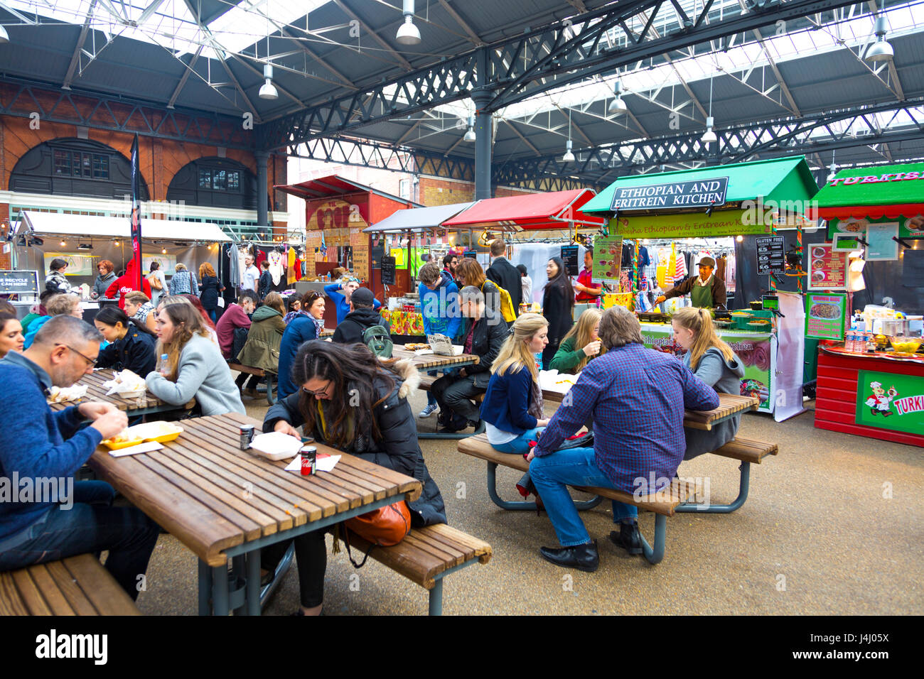 Menschen Sie sitzen und Essen Speiselokal in Spitalfields Market, London Stockfoto