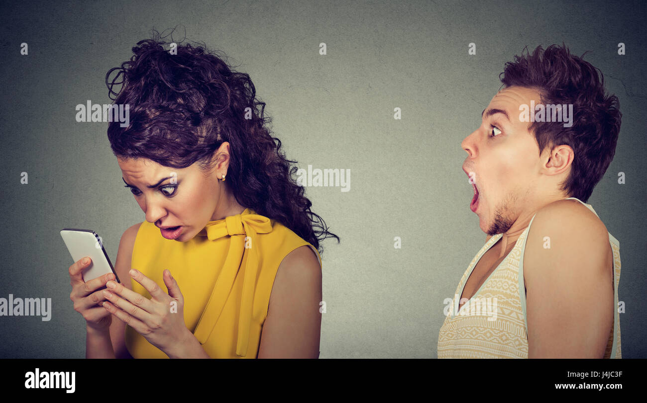 Schockiert Angst Mann Blick auf seine verärgert verrückte Freundin auf seinem Handy Spionage ist Stockfoto