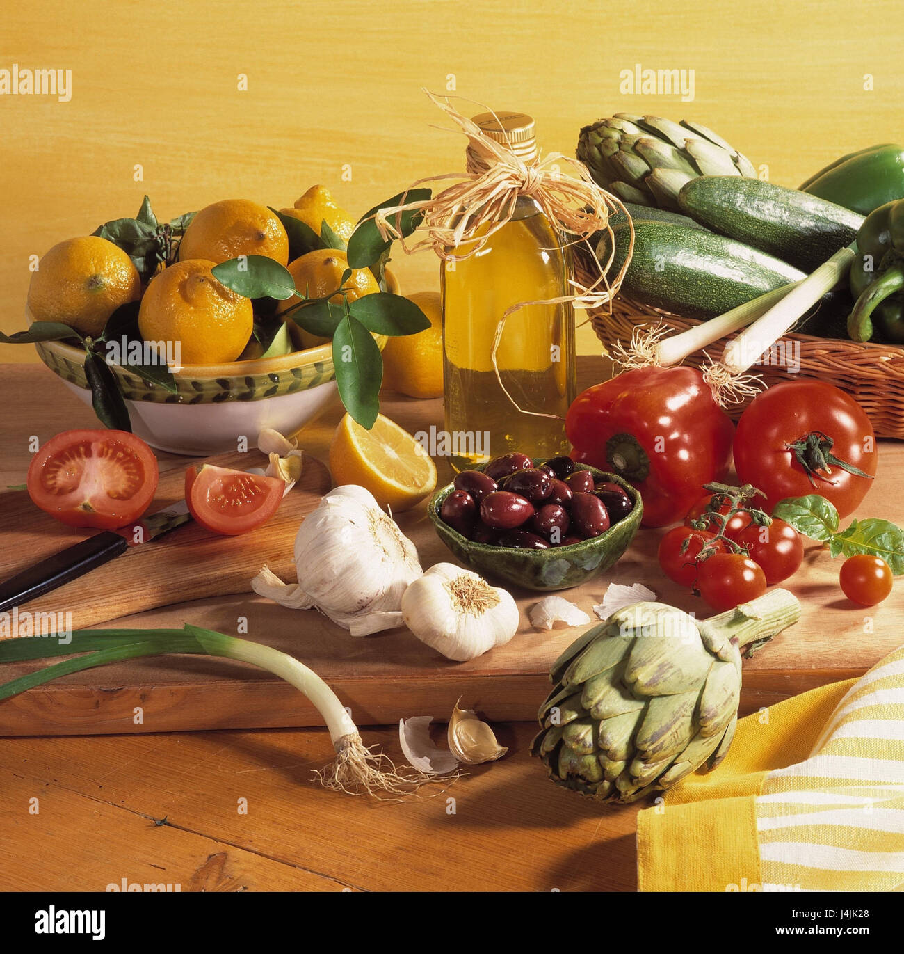 verschiedene Gemüse, hölzerne Sprungbrett schälen mit Zitronen, Speiseöl Paprika, Zucchini, Artischocken, Tomaten, Oliven, Knoblauch, Porree / Lauch Stockfoto