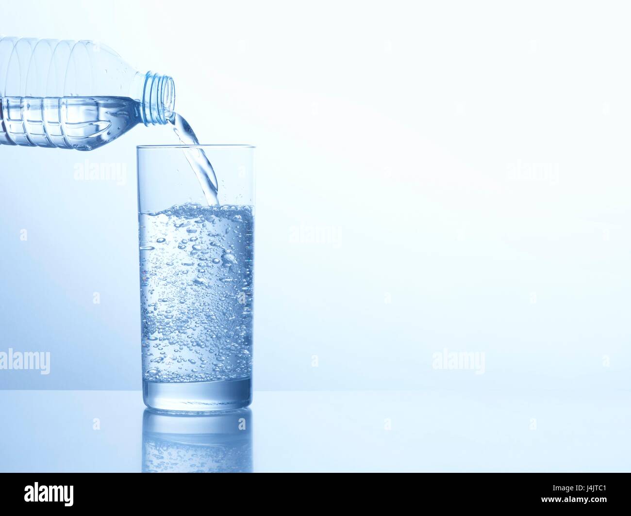 Gießt Wasser aus der Flasche in ein Glas, Studio gedreht. Stockfoto