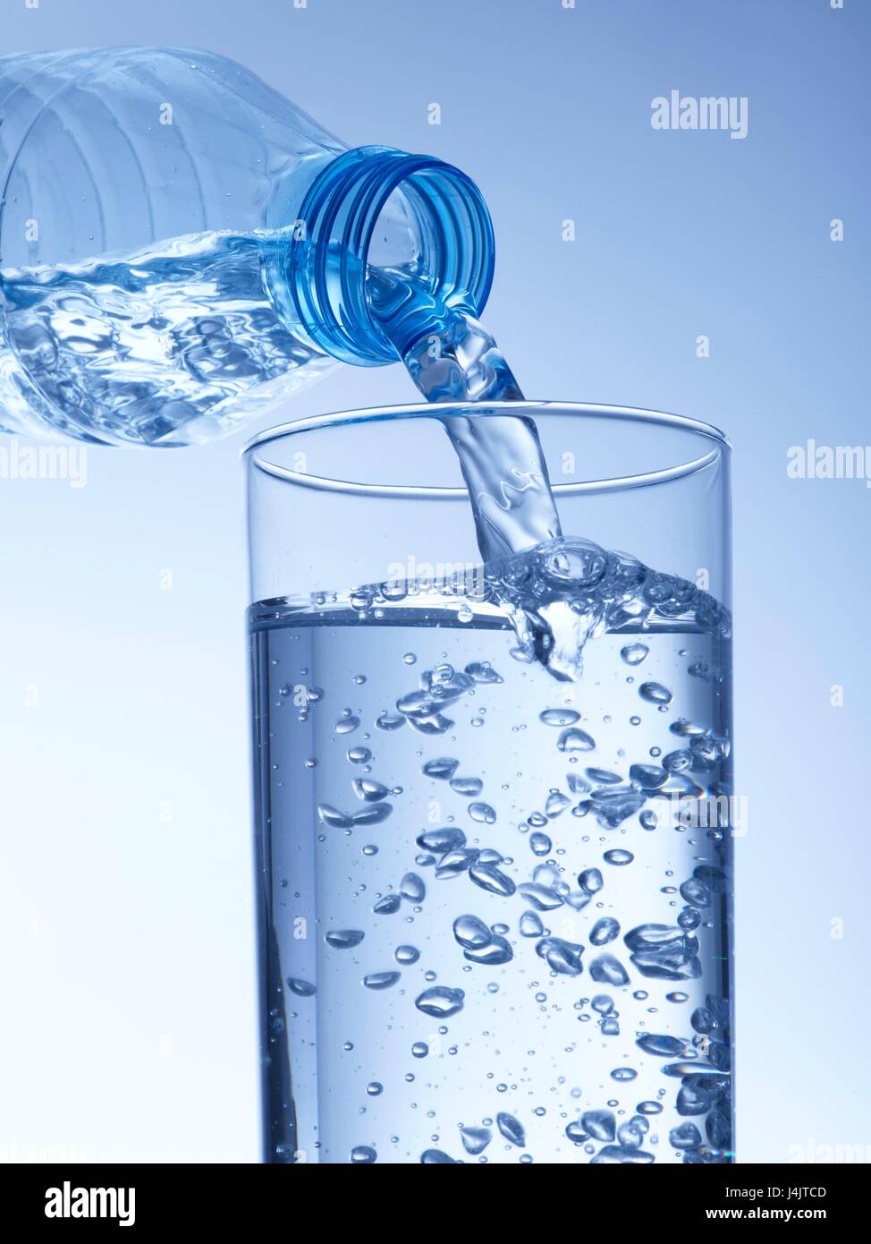 Gießt Wasser aus einer Plastikflasche in ein Glas, Studio gedreht. Stockfoto