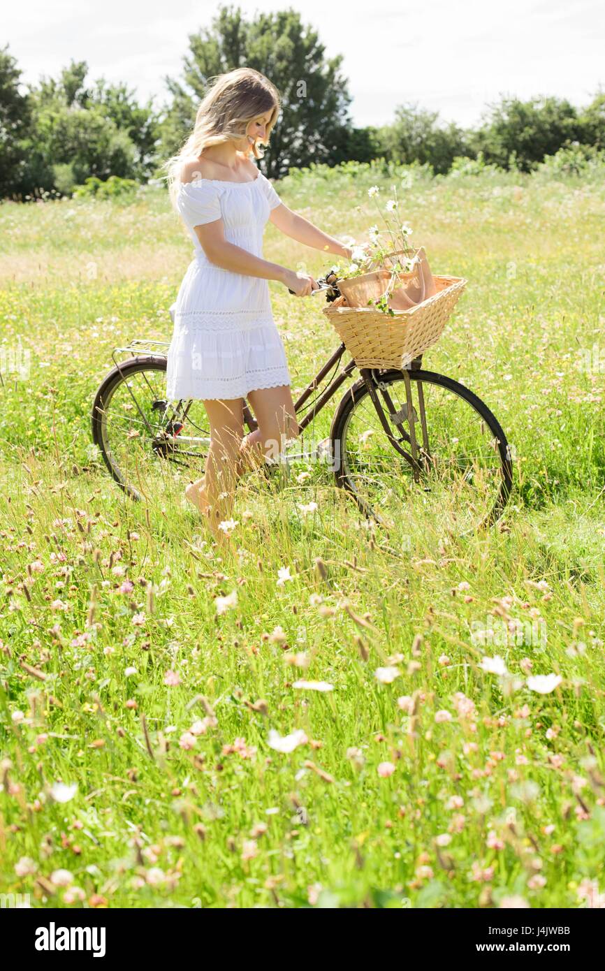 Junge Frau in der Wiese mit dem Fahrrad. Stockfoto