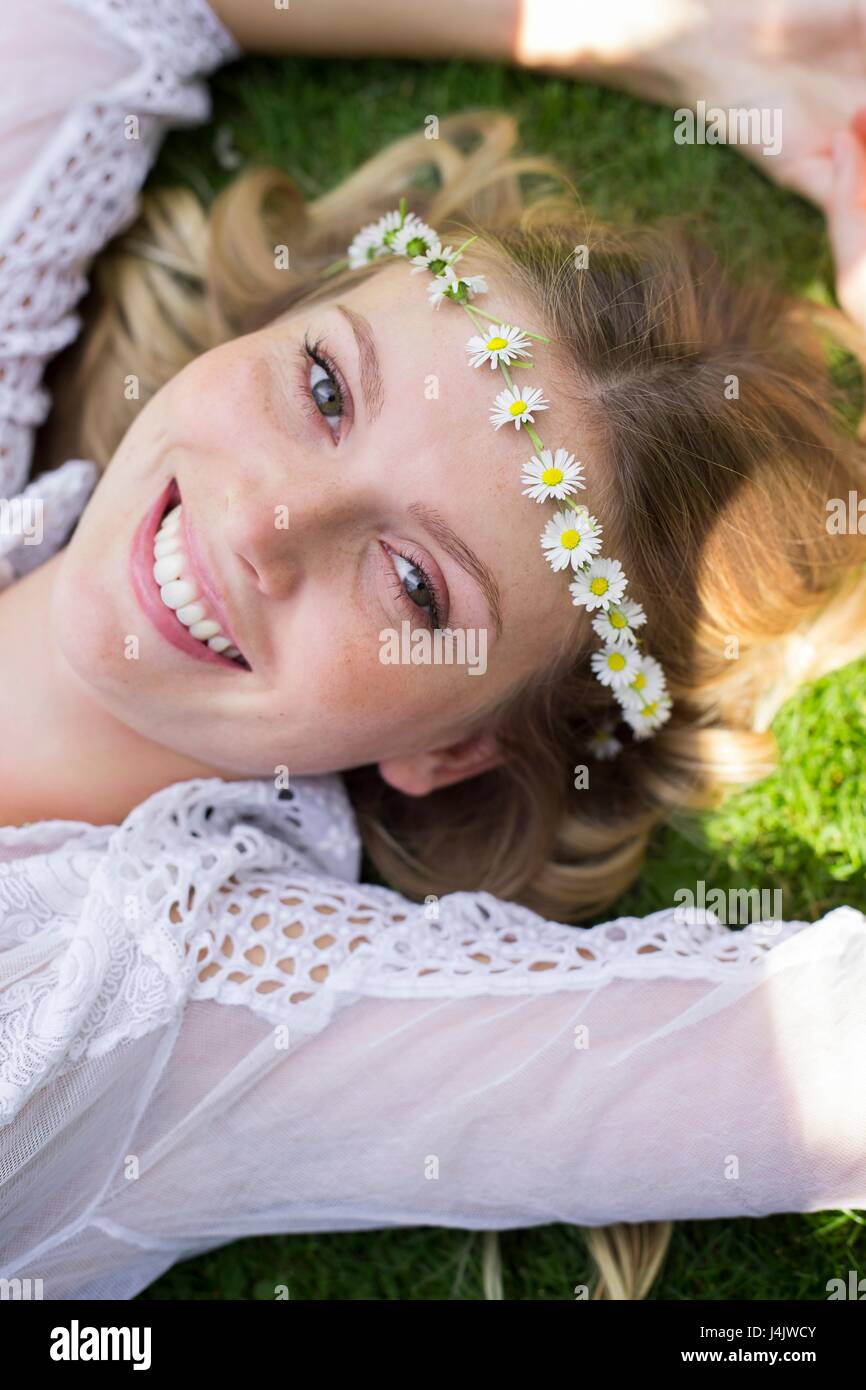 Junge Frau auf Gras daisy chain Tragen liegen. Stockfoto
