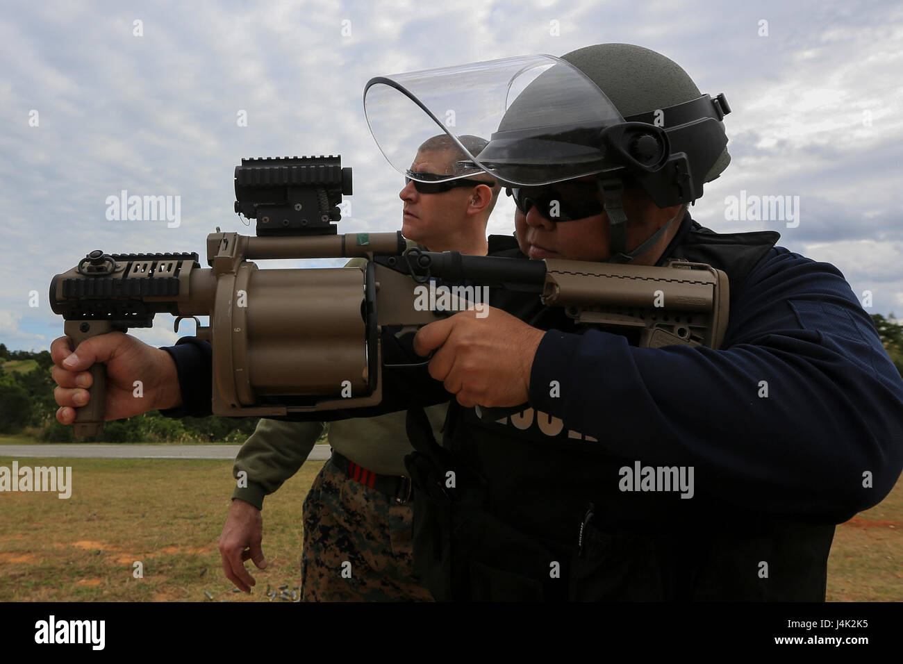 US Marine Gunnery Sgt. William Radebaugh, nicht-tödliche Waffen Instruktor, beobachtet, wie Satoshi Kinjo, japanische Wachmann, Torii Station in eine nicht-tödliche Waffen Instructor Kurs an Bord Camp Hansen, Okinawa, Japan, 17. Januar 2017 M32 Granatwerfer schießt. Der Kurs lehrt Personal die richtigen Techniken bei der Durchführung von Taser Training, Oleoresin Capsaicin Exposition und Riot Control Teamtaktik. (Foto: U.S. Marine Corps MCIPAC Bekämpfung der Kamera CPL. Allison Lotz/freigegeben) Stockfoto