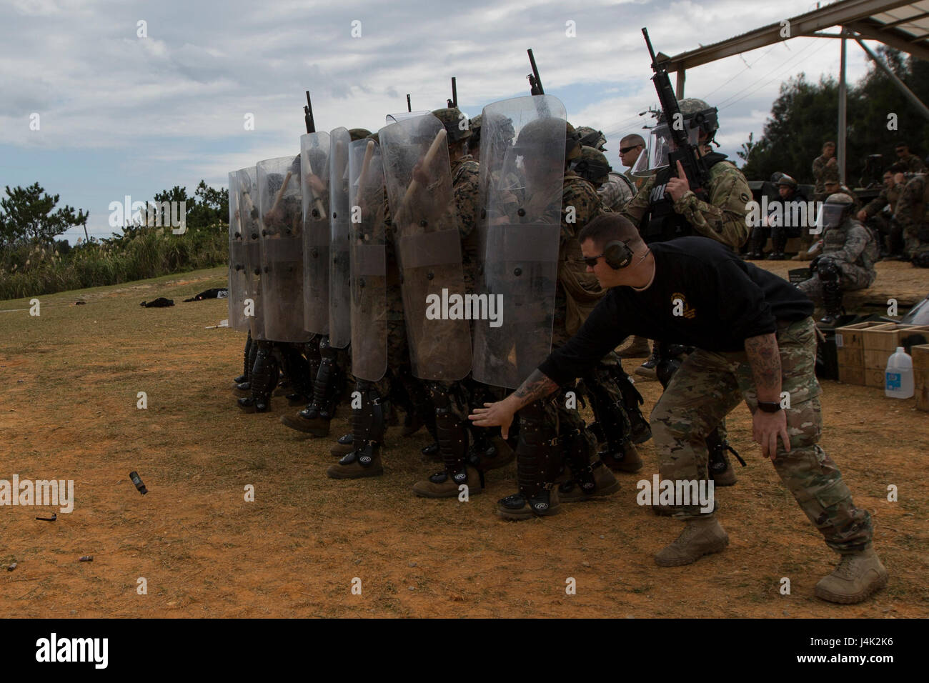 US Soldat Staff Sgt McQueen, nicht-tödliche Waffen Instruktor, wirft eine Flash-Bang-Granate vor der US-Marines, Matrosen, Soldaten, Flieger und japanische Wachleute wie sie Riot Control-Techniken in einer nicht-tödliche Waffen Instructor Kurs an Bord Camp Hansen, Okinawa, Japan, 17. Januar 2017 durchzuführen. Der Kurs lehrt Personal die richtigen Techniken bei der Durchführung von Taser Training, Oleoresin Capsaicin Exposition und Riot Control Teamtaktik. (Foto: U.S. Marine Corps MCIPAC Bekämpfung der Kamera CPL. Allison Lotz/freigegeben) Stockfoto