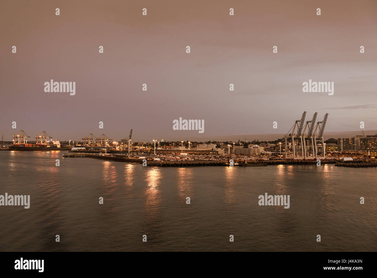 Auckland, Neuseeland - 6. März 2017: Überblick über den kommerziellen Hafen bei Sonnenuntergang mit Container-Terminals und Schiffe. Lichter an den Docks reflektiert in Stockfoto