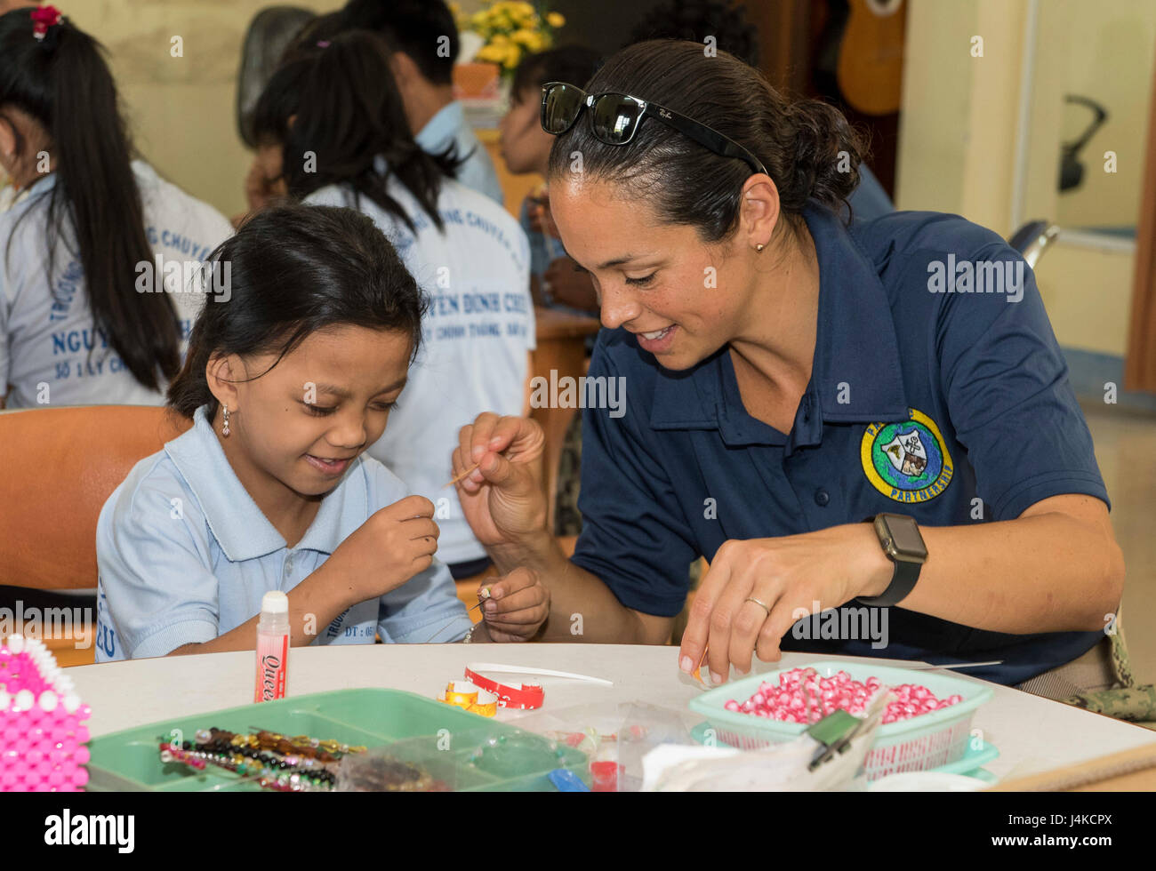 170510-N-OU129-131 DA NANG, Vietnam (10. Mai 2017) Lt. CMdR Lenaya Rotklein macht Armbänder und Ohrringe während einer Sitzung in Kunst und Handwerk an der Nguyen Dinh Chieu Specialized Schule während der Pazifischen Partnerschaft 2017 Da Nang kann 10. Pacific Partnership ist die größte jährliche multilaterale humanitäre Hilfe und Katastrophenschutz Bereitschaft Hilfsmission in Indo-Asien-Pazifik und zielt darauf ab, regionale Koordination in den Bereichen medizinische Eignung und Bereitschaft für natürliche und vom Menschen verursachte Katastrophen zu verbessern durchgeführt. (Foto: U.S. Navy Mass Communication Specialist 2. Klasse Joshua Fulton/freigegeben) Stockfoto